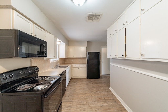 kitchen with black appliances, white cabinets, sink, decorative backsplash, and light wood-type flooring