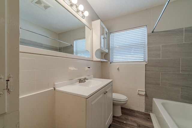 full bathroom with bathtub / shower combination, vanity, tile walls, hardwood / wood-style floors, and toilet