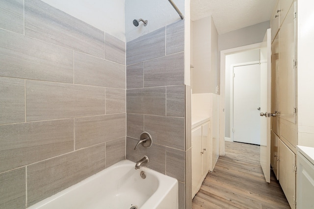 bathroom with hardwood / wood-style flooring, vanity, and tiled shower / bath