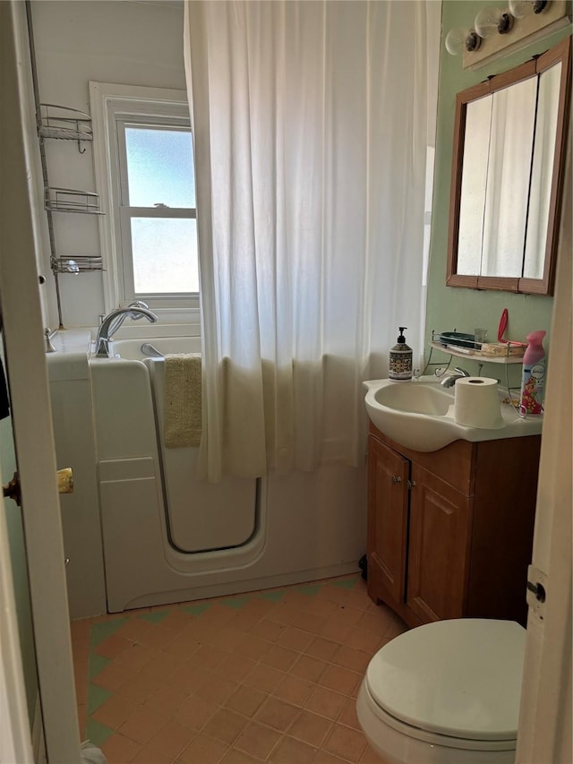 bathroom featuring tile patterned flooring, vanity, toilet, and a washtub