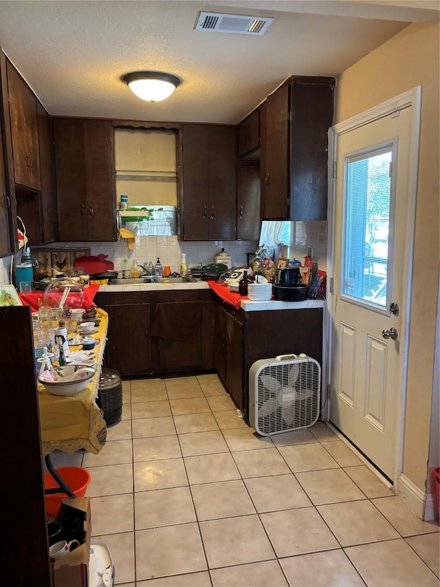 kitchen with dark brown cabinetry, sink, light tile patterned floors, and tasteful backsplash