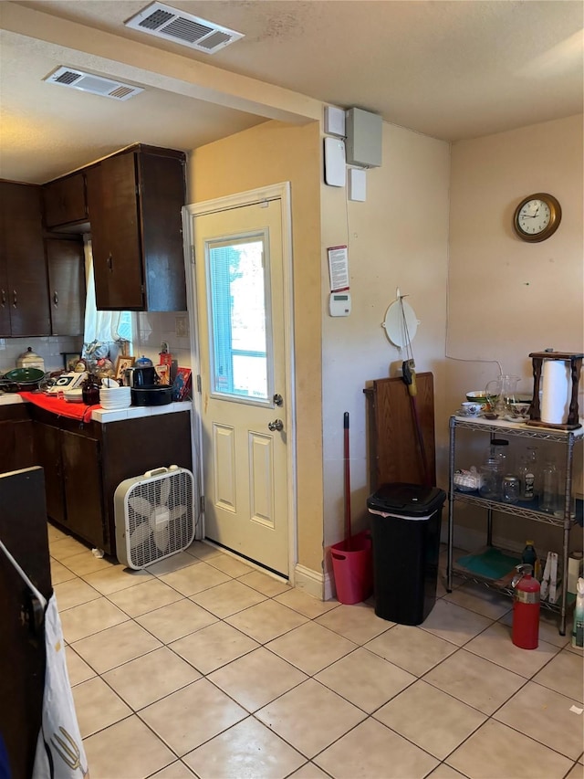 kitchen featuring decorative backsplash, dark brown cabinets, and light tile patterned floors