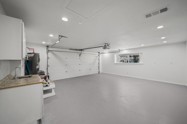 garage featuring electric water heater, sink, and a garage door opener