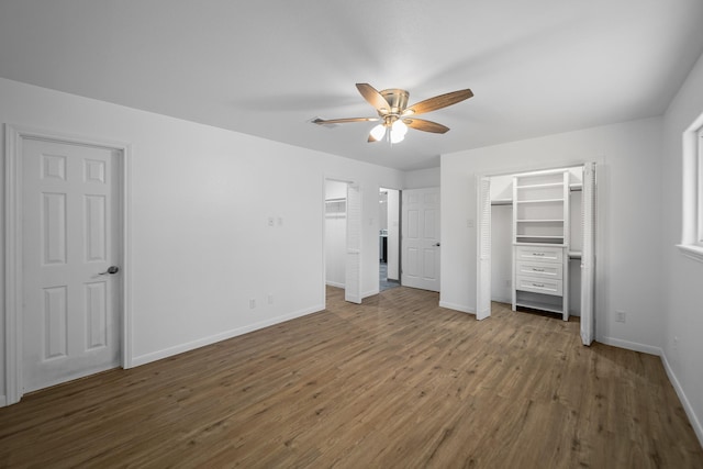 unfurnished bedroom featuring dark hardwood / wood-style flooring, a spacious closet, and ceiling fan