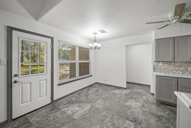 unfurnished dining area with ceiling fan with notable chandelier