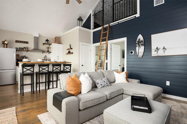 living room featuring dark hardwood / wood-style flooring, high vaulted ceiling, ceiling fan, and wood walls