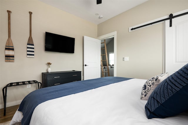 bedroom featuring a barn door and hardwood / wood-style floors