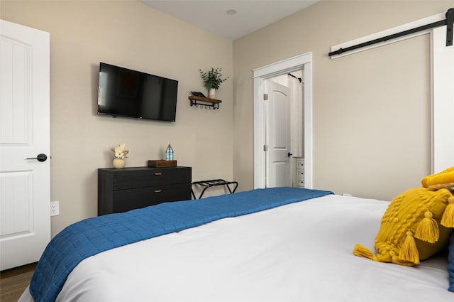 bedroom with a barn door and dark wood-type flooring