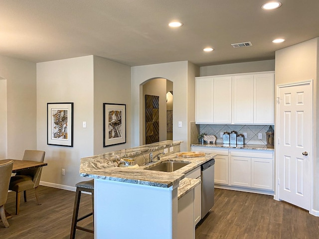 kitchen featuring white cabinets, a center island with sink, sink, stainless steel dishwasher, and dark hardwood / wood-style flooring