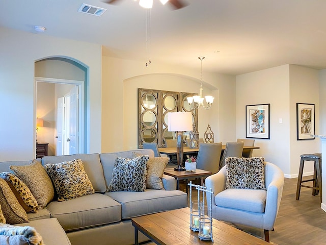 living room featuring wood-type flooring and ceiling fan with notable chandelier