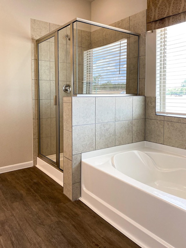 bathroom with wood-type flooring and shower with separate bathtub