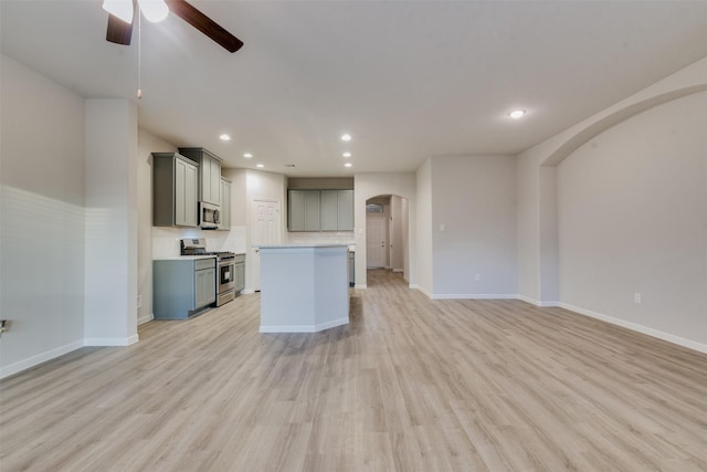 kitchen with appliances with stainless steel finishes, gray cabinetry, ceiling fan, light hardwood / wood-style floors, and a kitchen island