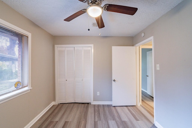 unfurnished bedroom with a textured ceiling, light wood-type flooring, a closet, and ceiling fan