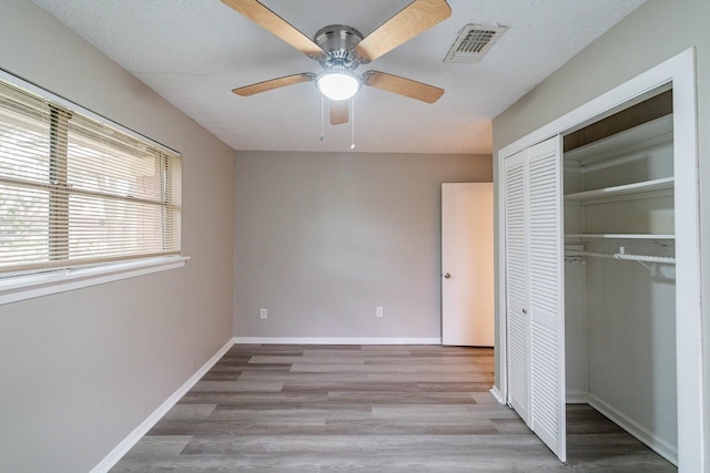 unfurnished bedroom featuring ceiling fan, a closet, and light wood-type flooring