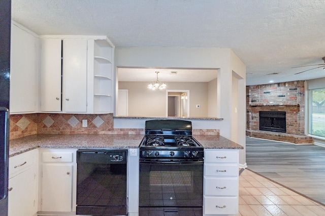 kitchen with backsplash, white cabinets, black appliances, and a brick fireplace