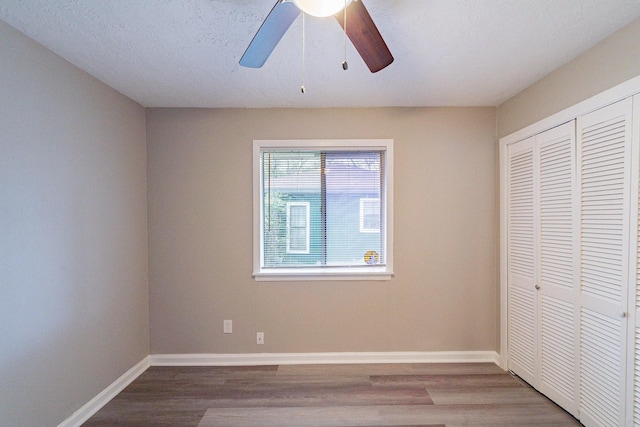 unfurnished bedroom featuring ceiling fan, a closet, hardwood / wood-style floors, and a textured ceiling