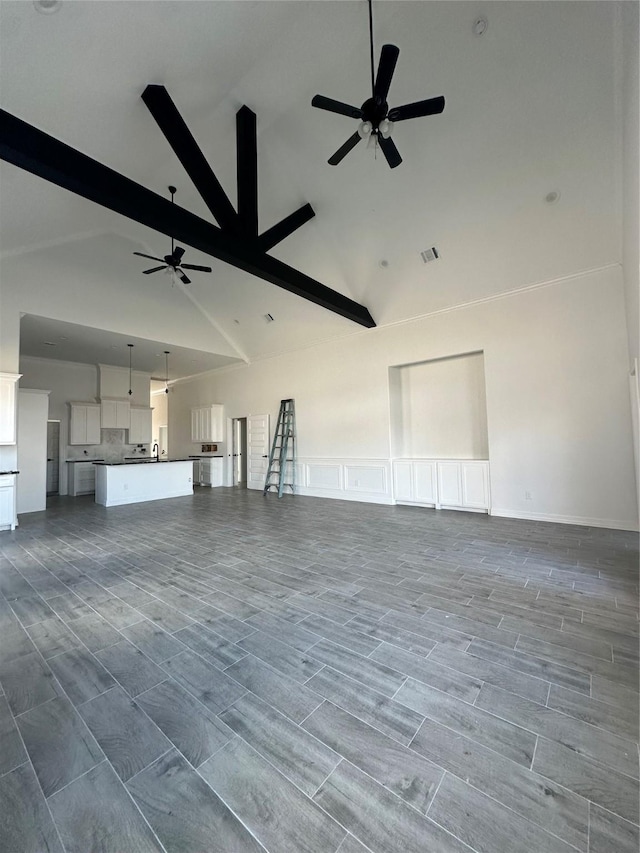 unfurnished living room with hardwood / wood-style floors, ceiling fan, beam ceiling, and high vaulted ceiling