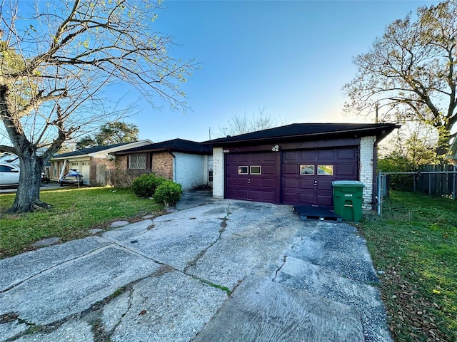 view of front facade with brick siding, concrete driveway, an attached garage, fence, and a front yard