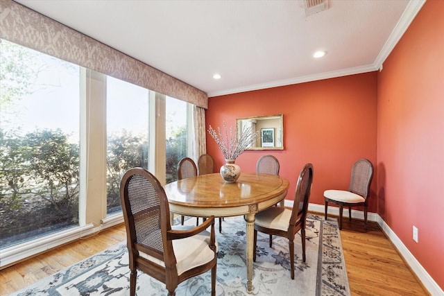 dining space with light hardwood / wood-style flooring and ornamental molding