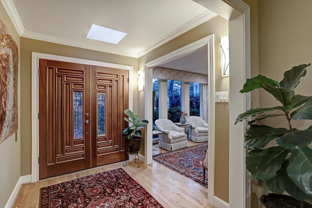 foyer featuring ornamental molding, light wood-type flooring, french doors, and a skylight