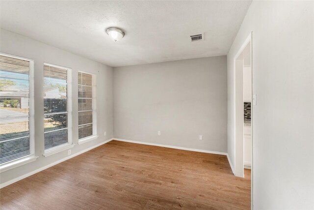 unfurnished room with a textured ceiling and light wood-type flooring