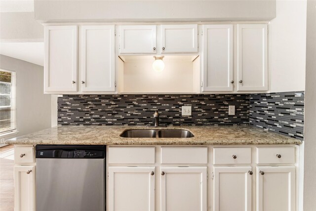 kitchen featuring light stone countertops, white cabinetry, stainless steel dishwasher, and sink