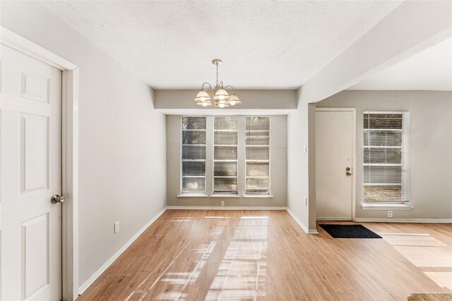 interior space featuring a wealth of natural light, an inviting chandelier, and light wood-type flooring