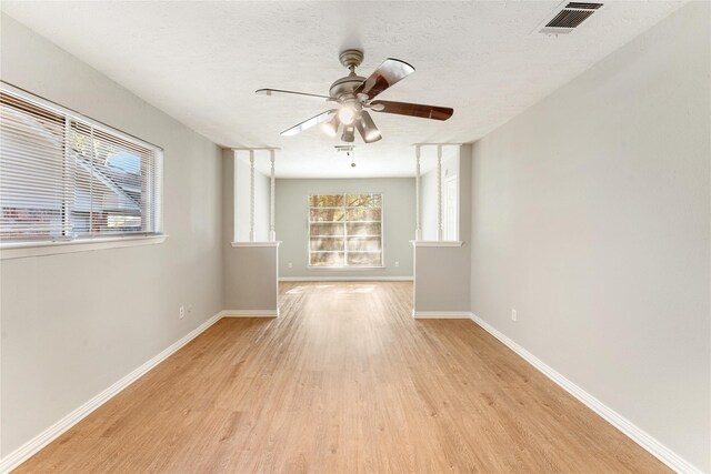 empty room featuring a textured ceiling, light wood-type flooring, and ceiling fan