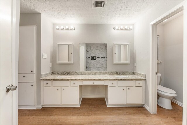 bathroom featuring vanity, toilet, wood-type flooring, and a textured ceiling