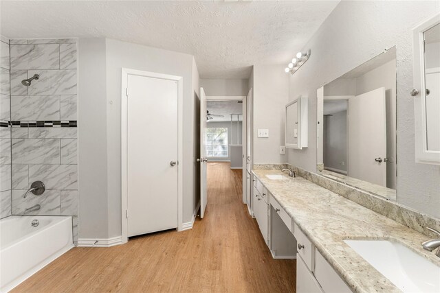 bathroom with vanity, tiled shower / bath combo, a textured ceiling, and hardwood / wood-style flooring