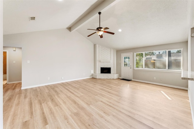 unfurnished living room with vaulted ceiling with beams, ceiling fan, light wood-type flooring, a textured ceiling, and a fireplace