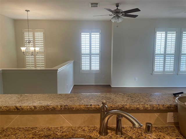 interior space with ceiling fan with notable chandelier and hanging light fixtures