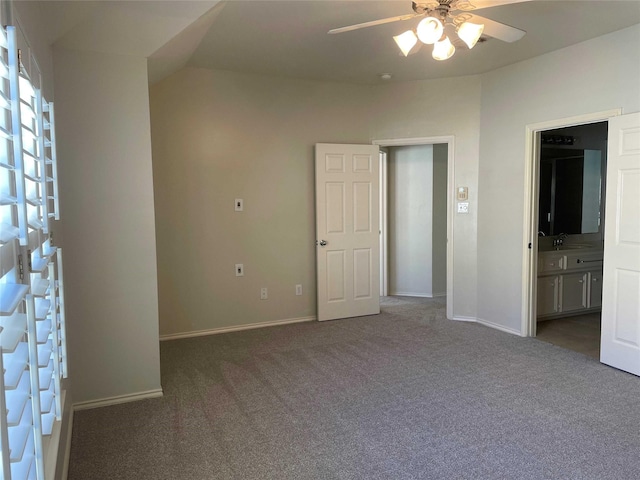 interior space featuring vaulted ceiling, dark carpet, ceiling fan, and sink