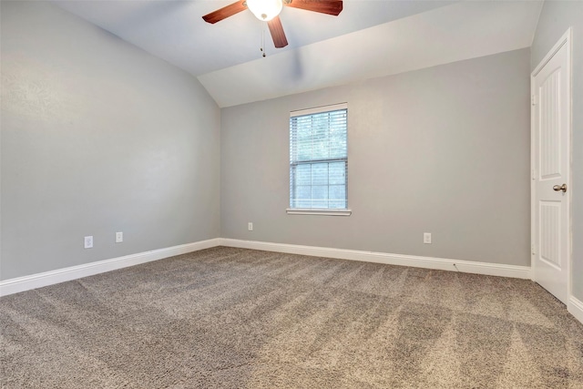 empty room with lofted ceiling, ceiling fan, carpet flooring, and baseboards