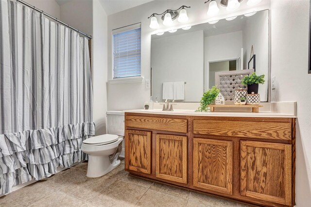 bathroom with a sink, double vanity, tile patterned flooring, and toilet