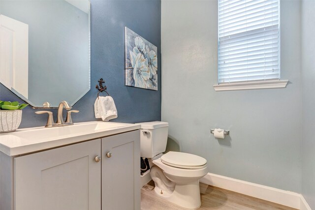 bathroom with toilet, baseboards, wood finished floors, and vanity