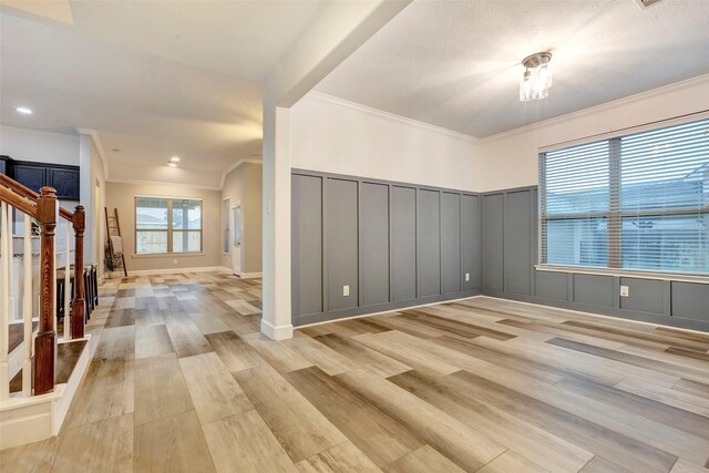 spare room with light wood-style floors, stairway, a decorative wall, and crown molding