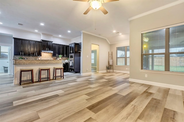 kitchen with tasteful backsplash, visible vents, a kitchen breakfast bar, open floor plan, and light wood-type flooring