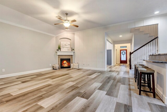 living area featuring stairs, light wood finished floors, a fireplace, and baseboards