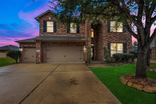 traditional-style house featuring a yard, driveway, brick siding, and an attached garage