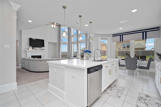 kitchen featuring sink, hanging light fixtures, stainless steel dishwasher, an island with sink, and white cabinets