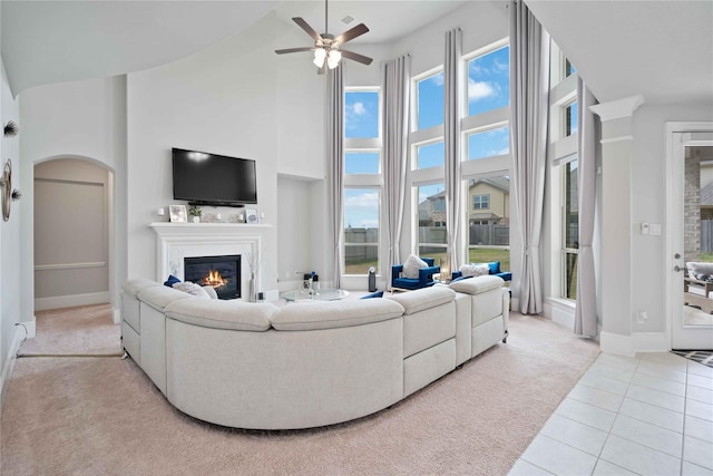 living room with a wealth of natural light, light tile patterned flooring, a high ceiling, and ceiling fan