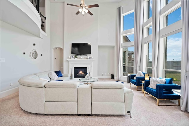 living room with ceiling fan, carpet floors, and a high ceiling