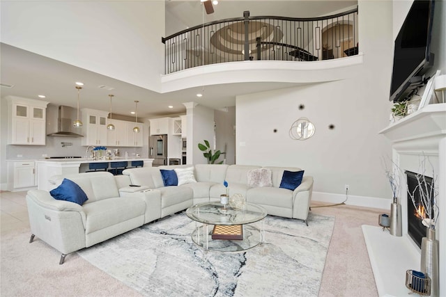 carpeted living room featuring a premium fireplace and a high ceiling