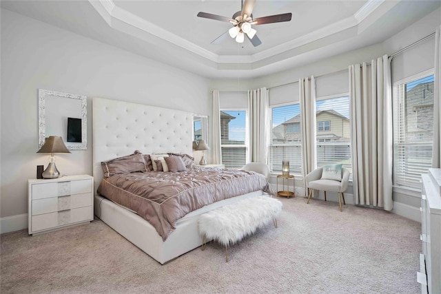 carpeted bedroom with a raised ceiling, ceiling fan, and ornamental molding