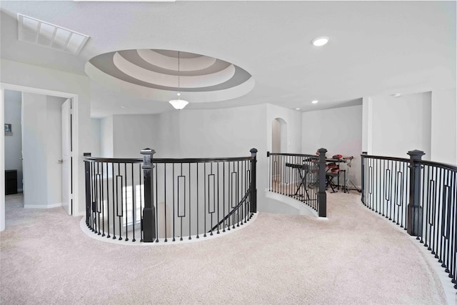 corridor featuring light colored carpet and a tray ceiling