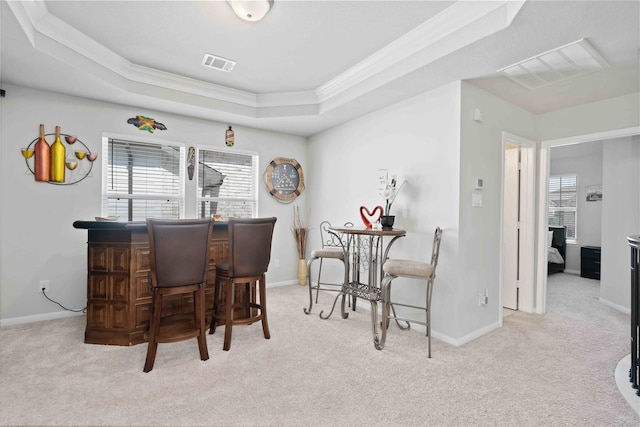 bar featuring light colored carpet, ornamental molding, and a tray ceiling