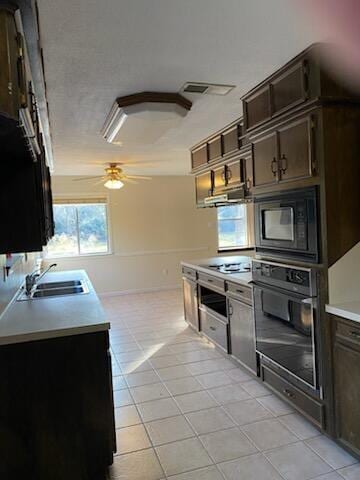 kitchen with dark brown cabinets, ceiling fan, sink, black appliances, and light tile patterned floors