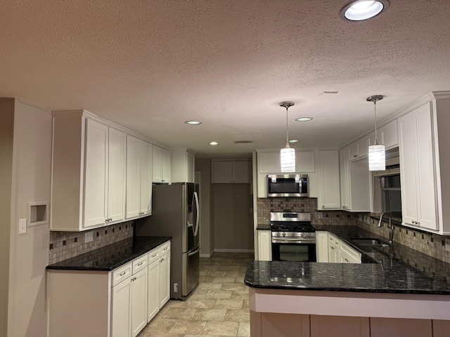 kitchen featuring kitchen peninsula, appliances with stainless steel finishes, pendant lighting, white cabinets, and sink