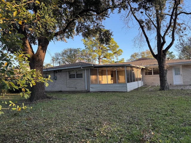 back of house featuring a yard and a sunroom